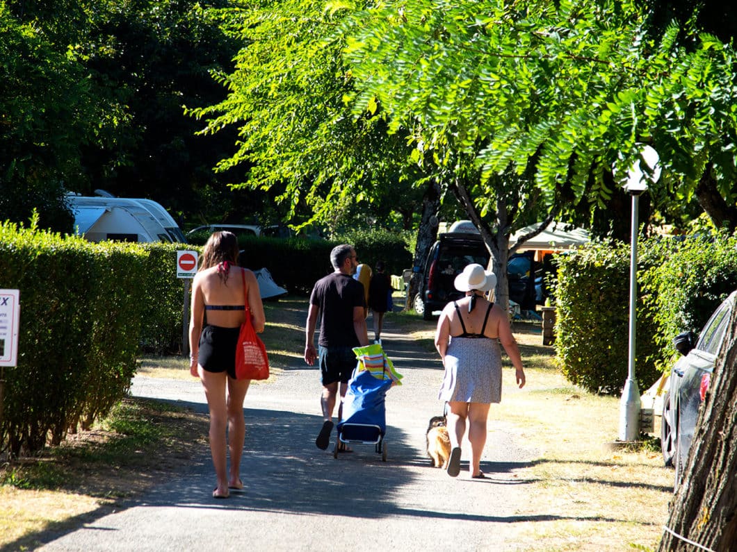 Vacanciers dans les allées du camping La Bouysse en direction de la piscine