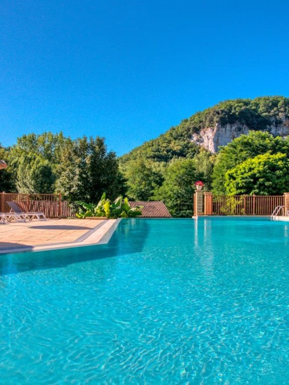 Piscine chauffée du camping La Bouysse face à la falaise, dans le Périgord Noir