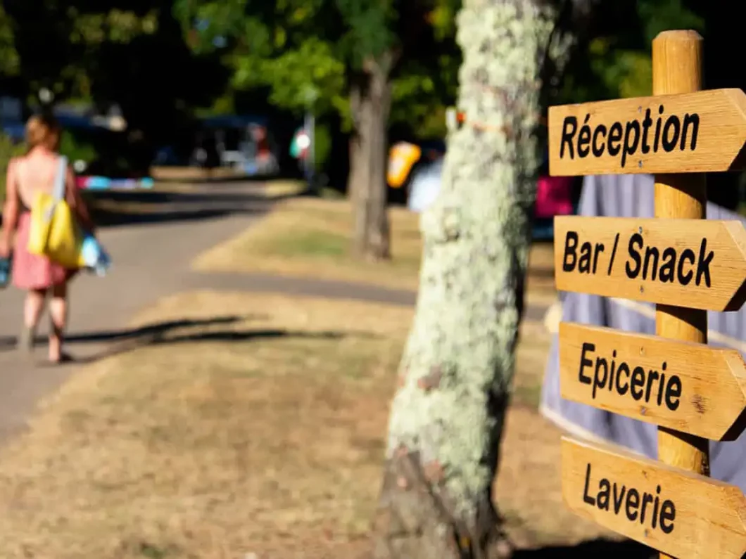 Panneau indiquant la réception, le bar-snack, l’épicerie et la laverie du Camping La Bouysse